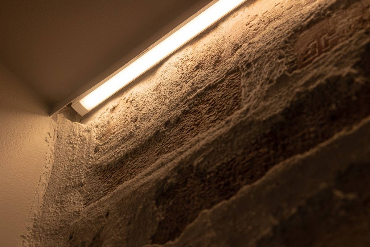 Close-up of an LED strip installation on an accent wall. The LED strip is mounted in a surface-mounted aluminum profile between the trim and the wall.