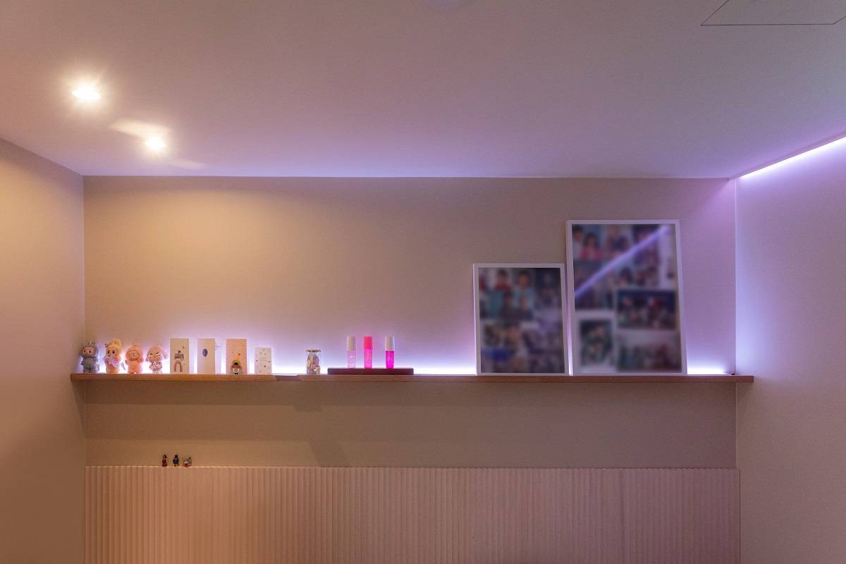 An LED strip emitting purple light runs around the room, and there are also two spotlights on the ceiling.