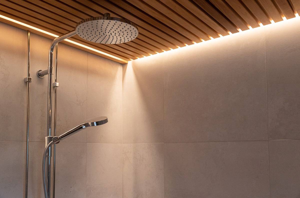 LED strips are embedded in the slatted ceiling of the shower area.