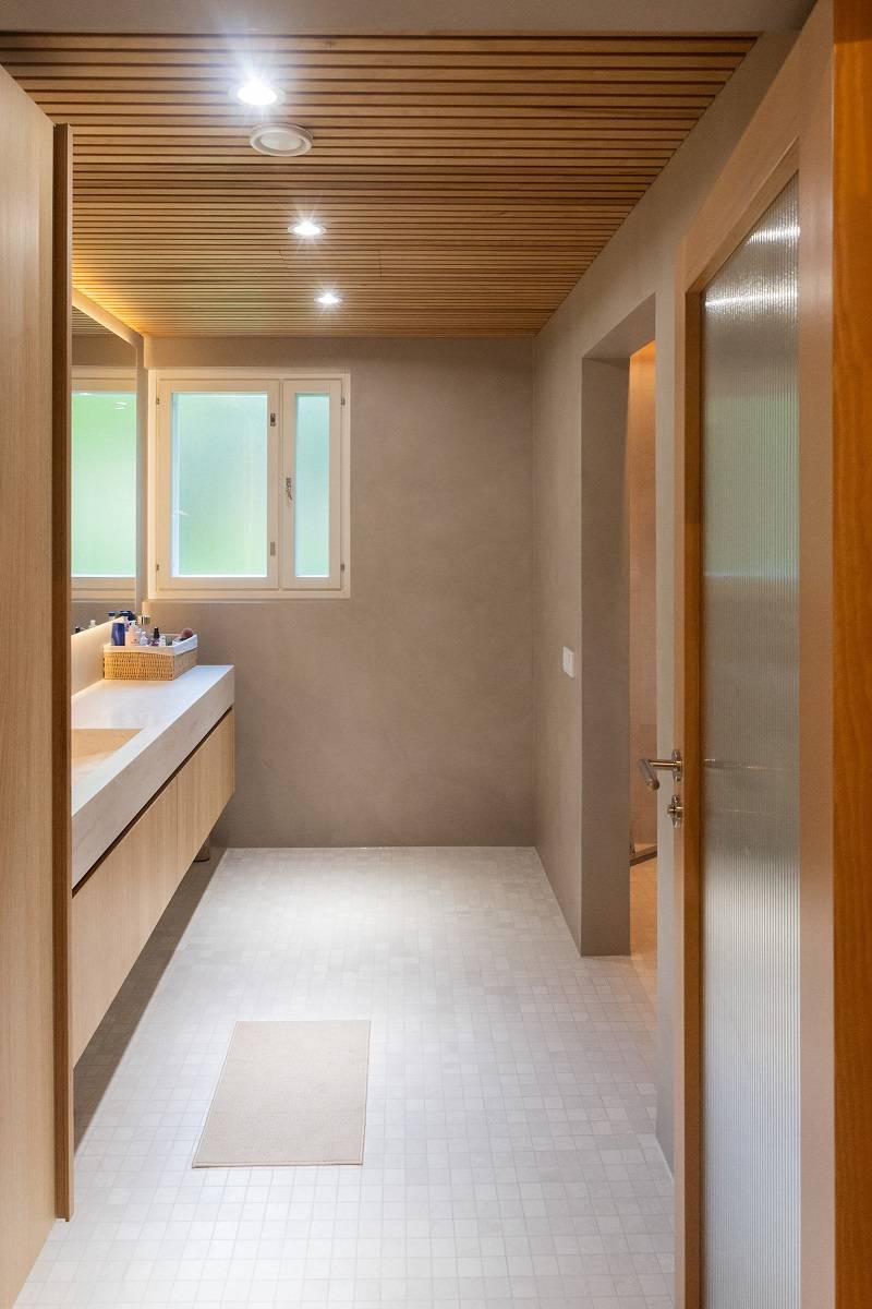 Spotlights and an LED strip behind the mirror illuminate the area in front of the sink in the bathroom.