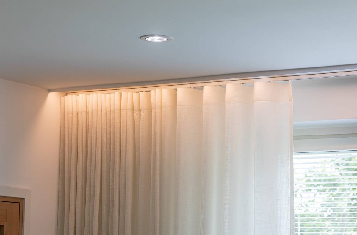 Downlight on the living room ceiling. An LED strip is installed behind the molding in front of the curtain, hiding the light source.