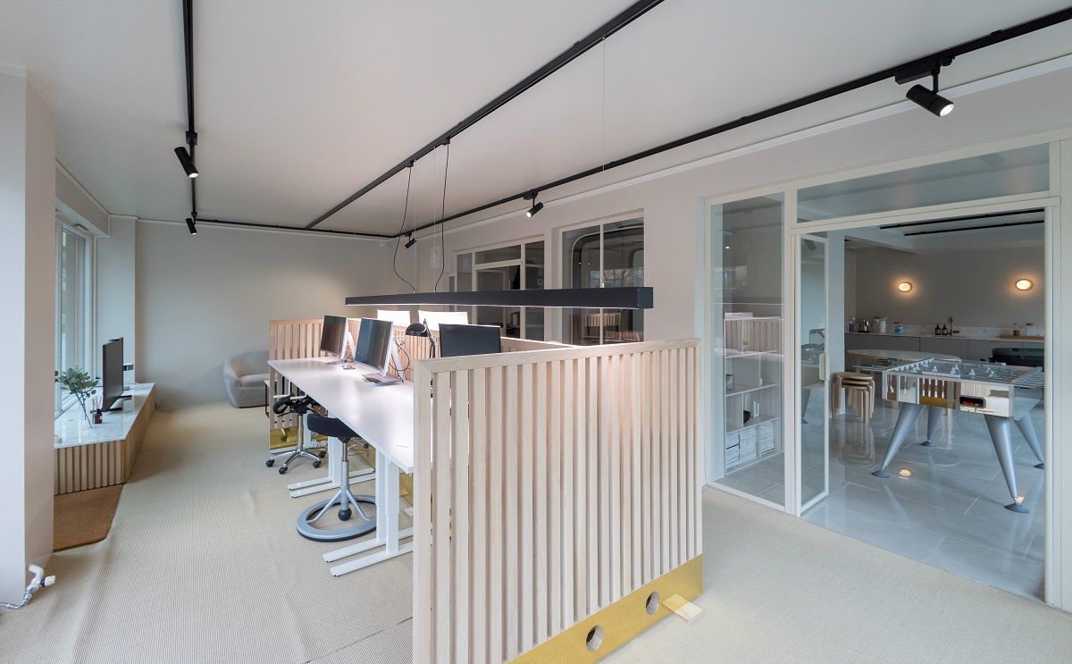 Office space with a three-phase track with spotlights on the ceiling and a pendant light on a long desk.