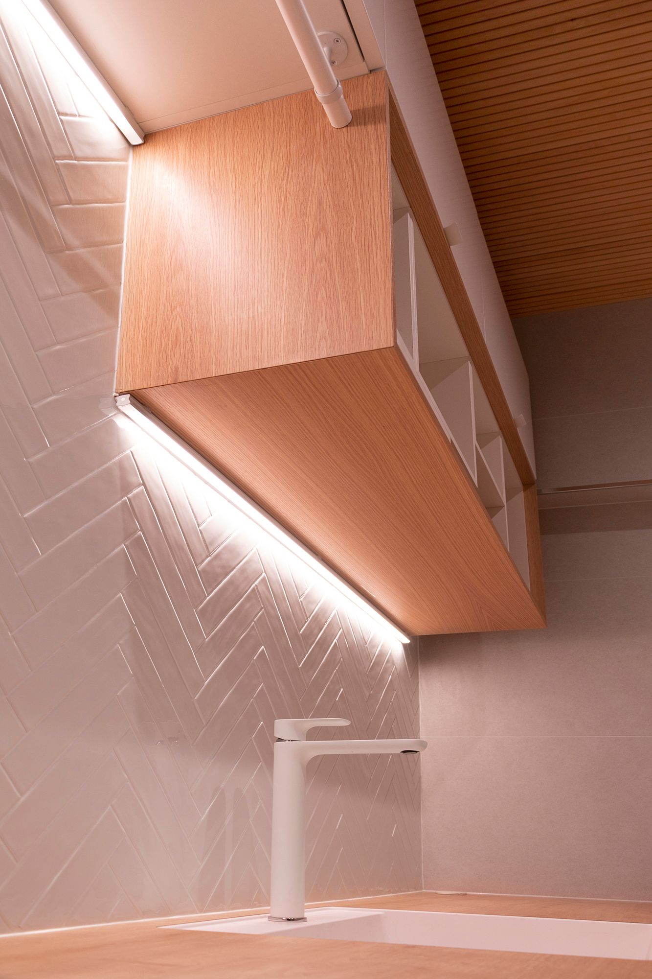 Two different levels of led strips in the corner of the cabinet and the wall. The led strips also accentuate the textured tile. Ledstore.fi