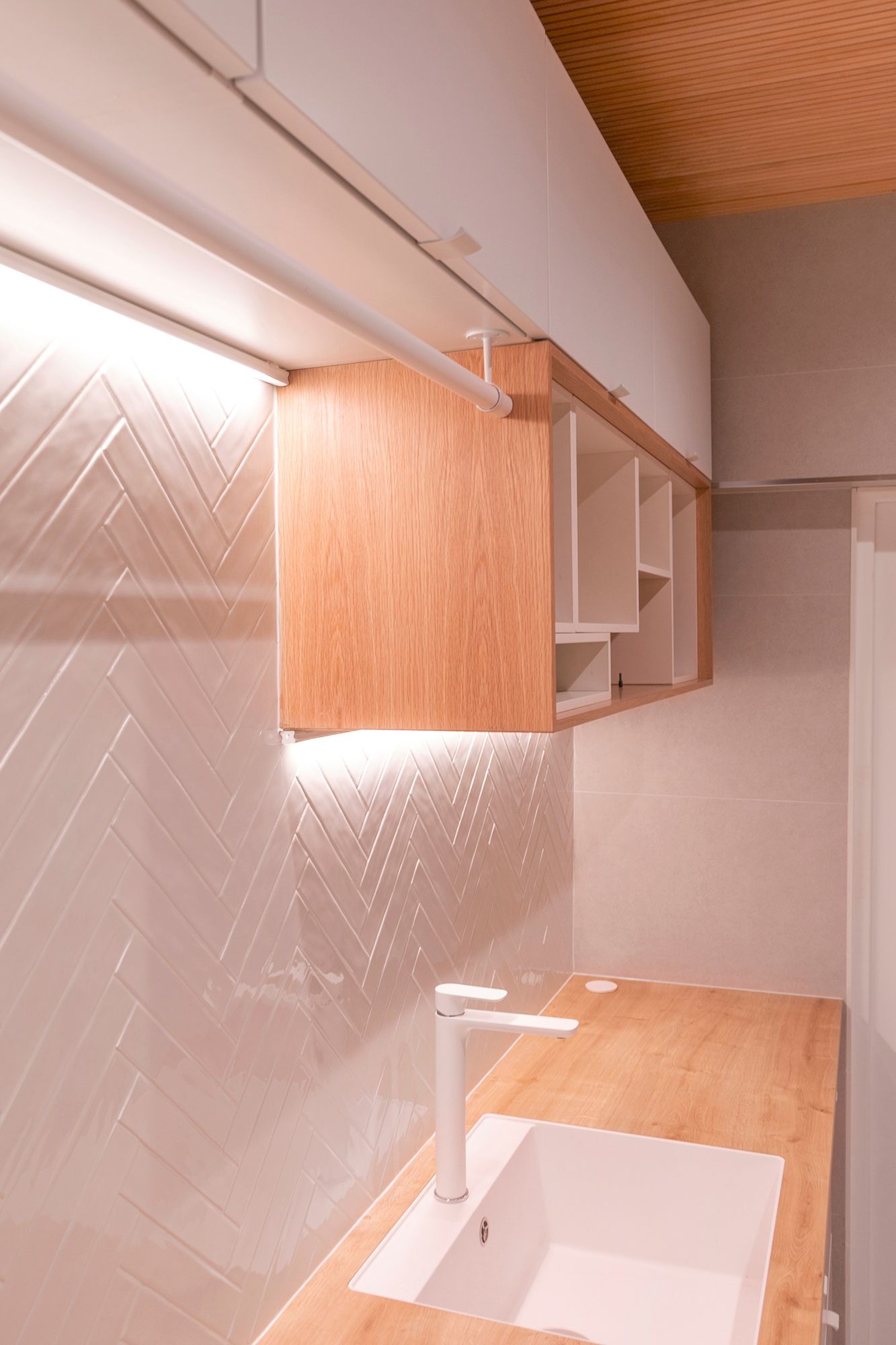 Two levels of LED strips mounted underneath the cabinets illuminate the worktop and highlight the textured tiles.