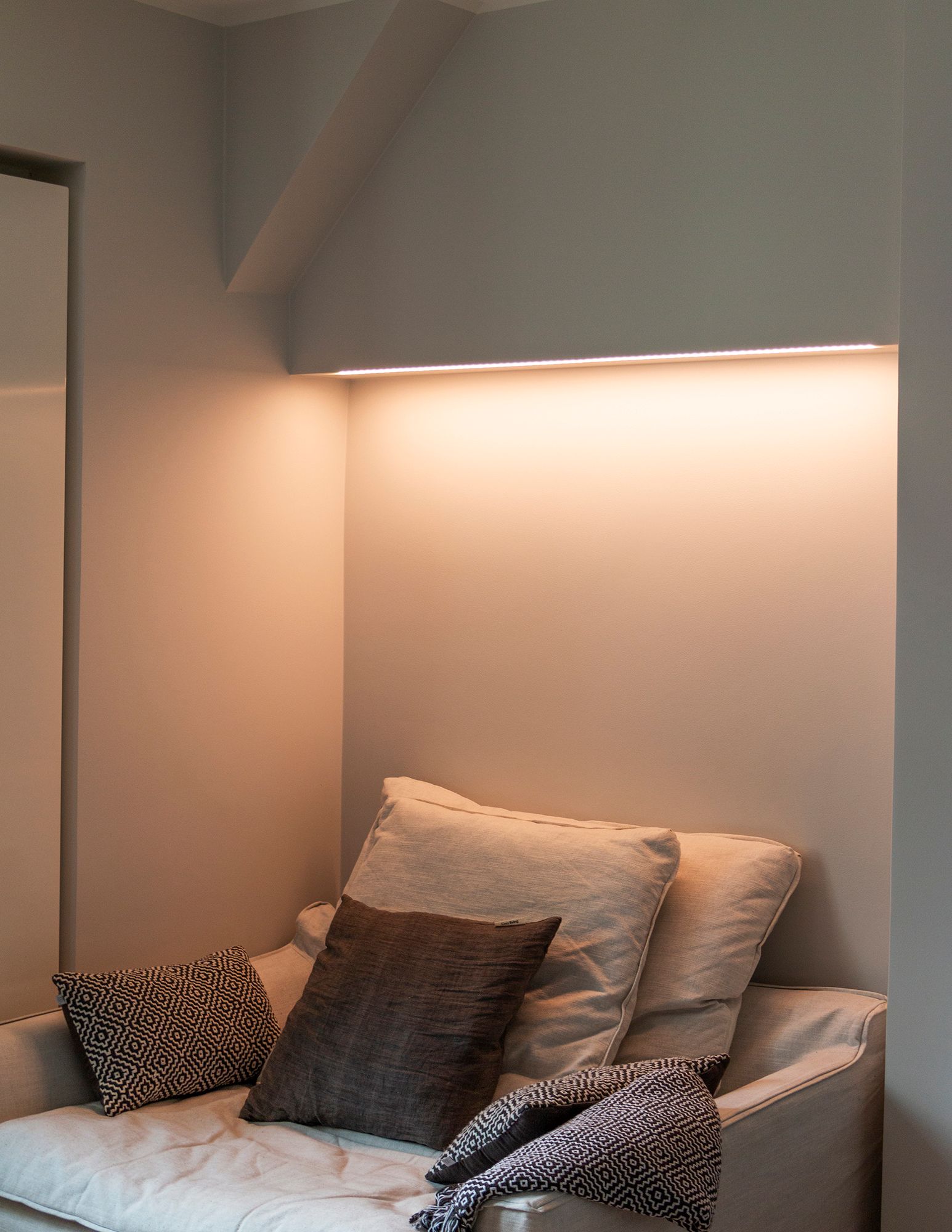 Bedroom with colour temperature adjustable mood lighting above the bed, LED strip mounted on the bottom of the cabinet in a low profile surface. The light has a warm tone in the picture. Ledstore.fi