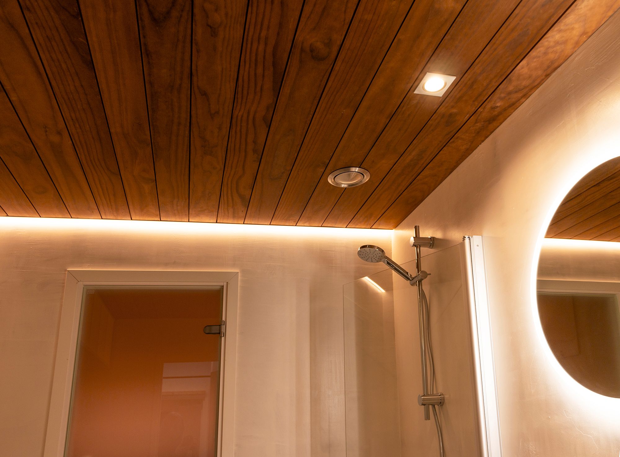 Edge profile with LED strip illuminating the shower combined with a light mirror and ceiling pots. Ledstore.fi