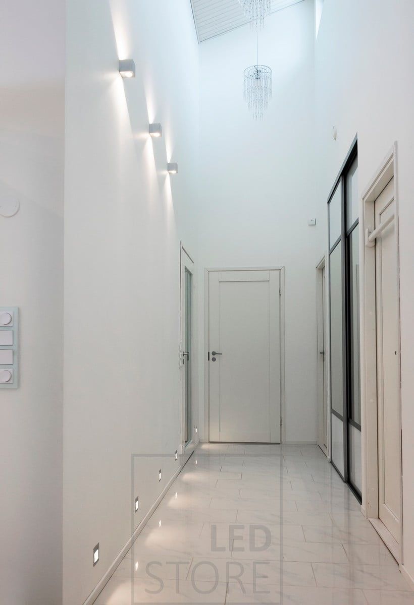 IN-WALL recessed led wall luminaires creating indirect light in the corridor at floor level. Above them, CUBIC led wall lights illuminating in two directions, highlighting the height of the space. Ledstore.fi