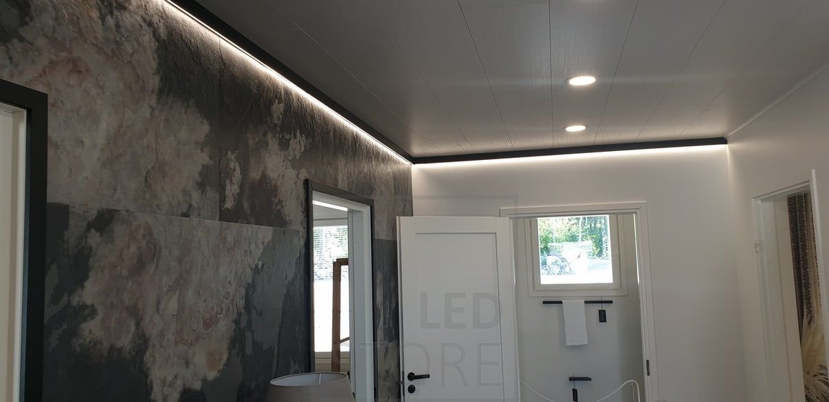 A decorative and linear black wall profile with an LED strip light providing indirect light. Ledstore.fi