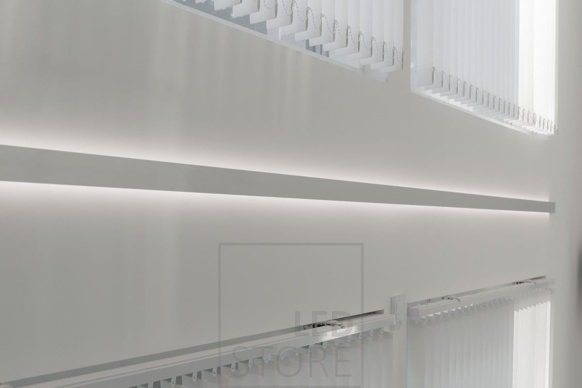 A bi-directional wall profile for LED strip lights, installed between windows. The light is atmospheric and indirect. Ledstore.fi