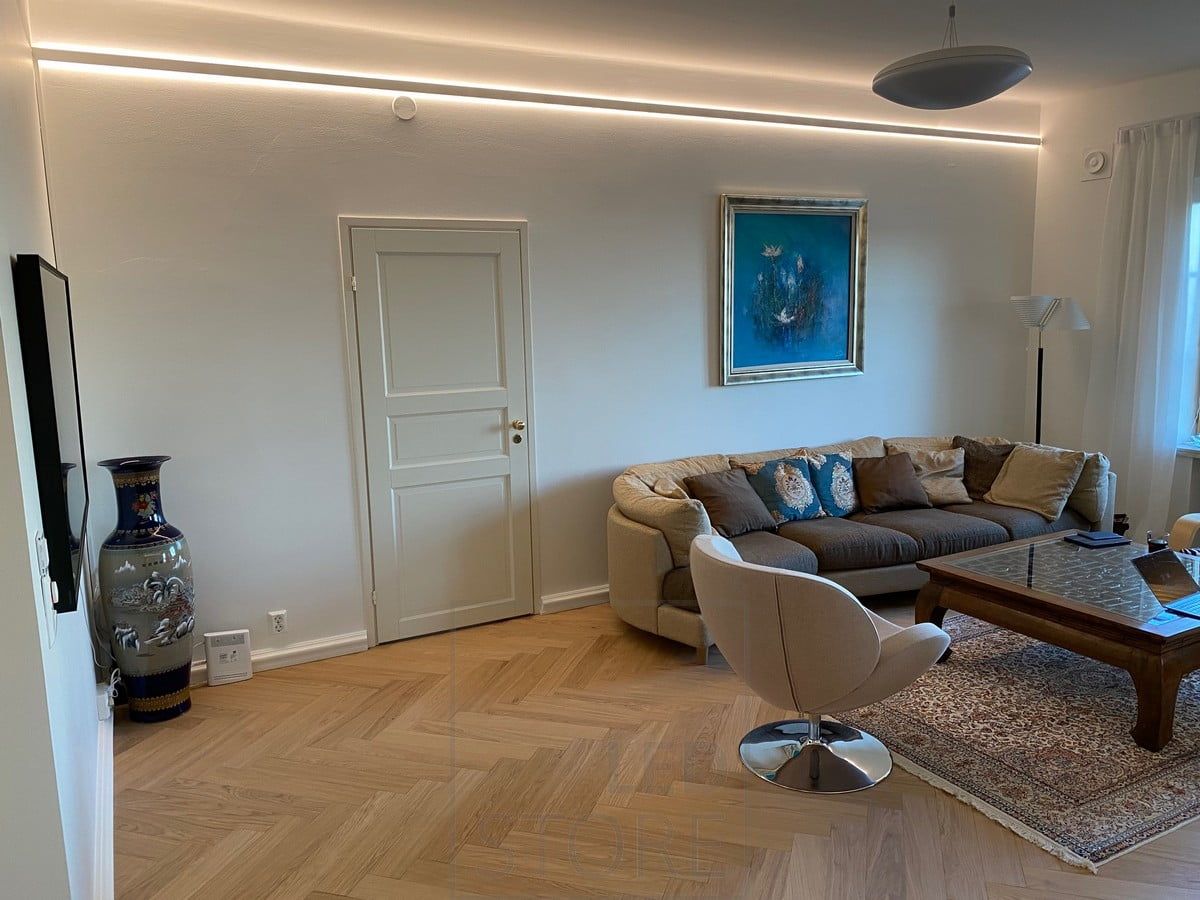 A two-way illuminated aluminium profile brought slightly down from the ceiling. Led strips illuminate indirect light throughout the space. Ledstore.fi
