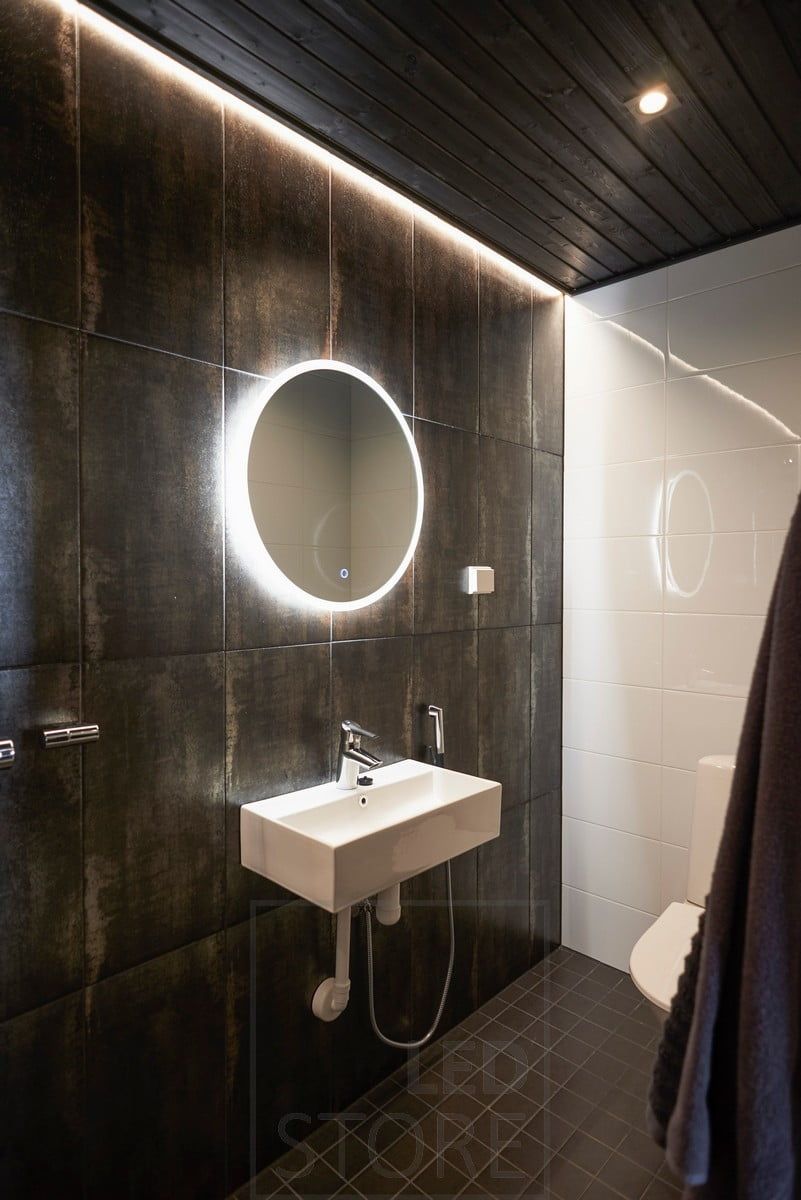 Dark bathroom atmospherically lit with spotlighting and indirect light. The light mirror has a defogging function that keeps the mirror bright when coming out of the sauna or shower. Ledstore.fi