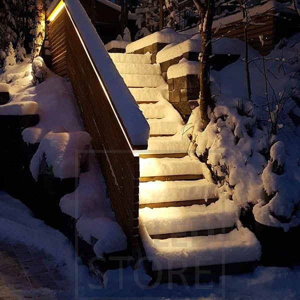 Outdoor lighting with a LED strip illuminating indirect light on the handrail of an outdoor staircase. Ledstore.fi