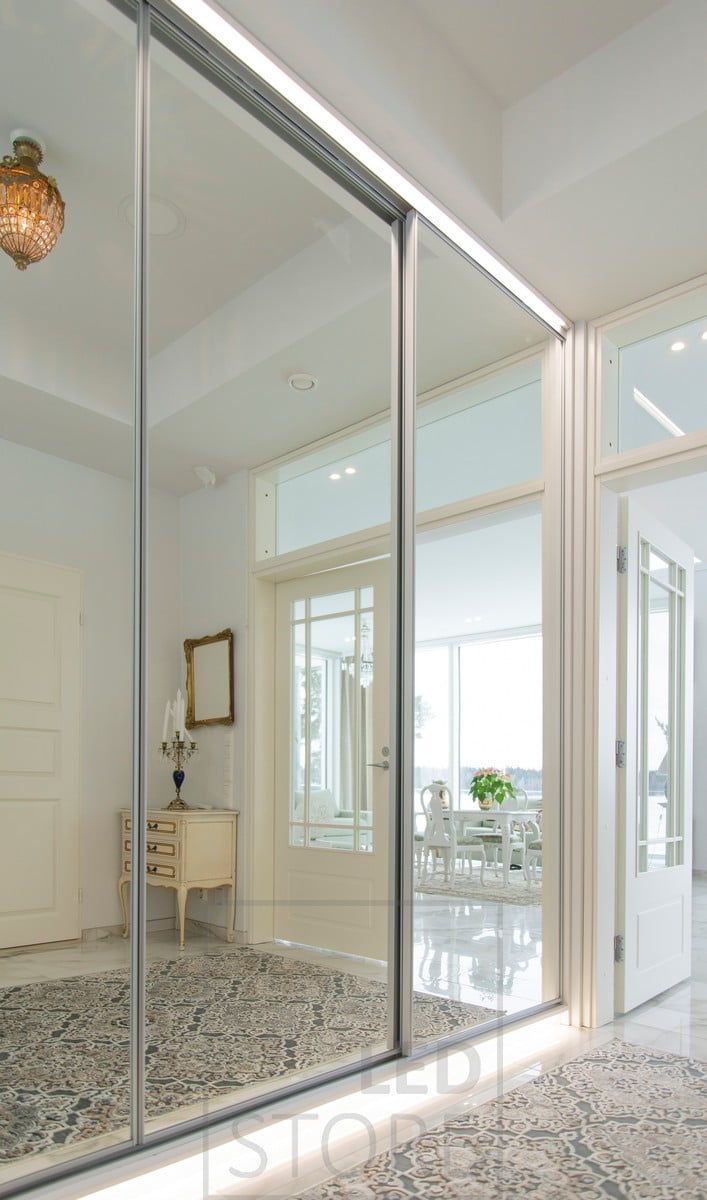 The base of the cabinet and the top of the cabinet are illuminated by LED strip lights providing soft, indirect light in the hallway. Ledstore.fi