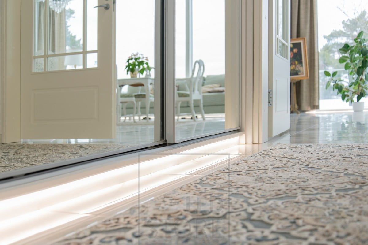 A plinth-mounted LED strip illuminates the hallway with soft, atmospheric indirect light. Ledstore.fi