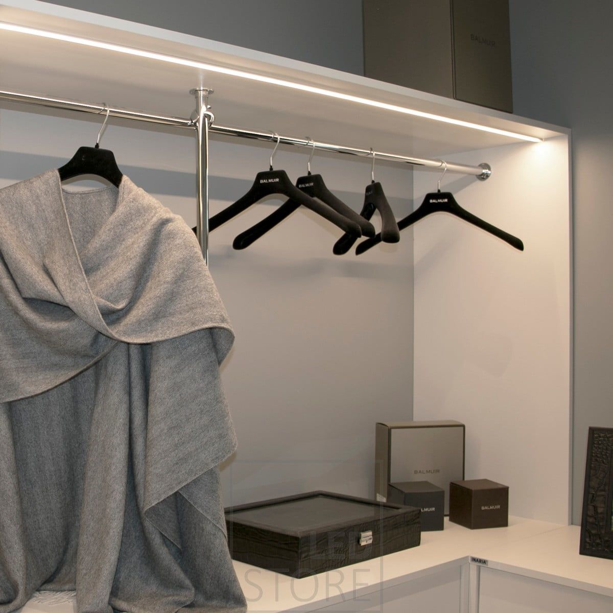 Led ribbon on a surface profile at the front edge of the cabinet, illuminating the open wardrobe. Ledstore.fi