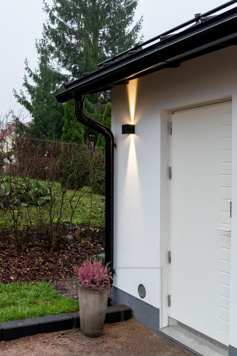 A black FUNK wall lamp with bi-directional lighting to highlight and illuminate the door. Ledstore.fi