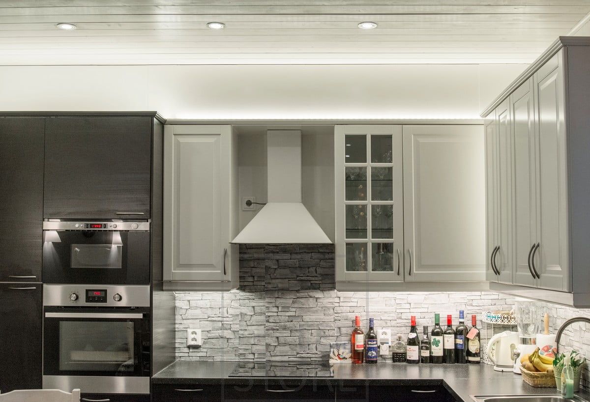 Kitchen worktop lighting combined with LED strips on top of the cabinets and spotlights. Ledstore.fi