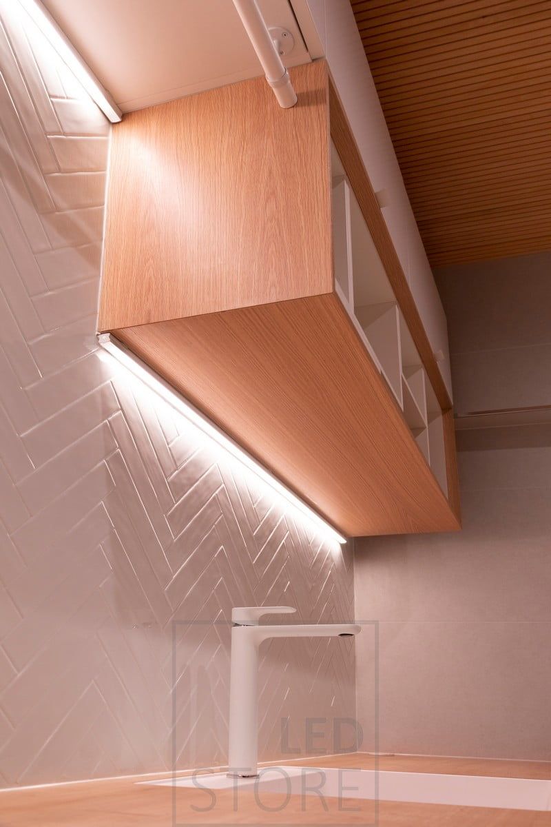 Two different levels of led strips in the corner of the cabinet and the wall. The led strips also accentuate the textured tile. Ledstore.fi