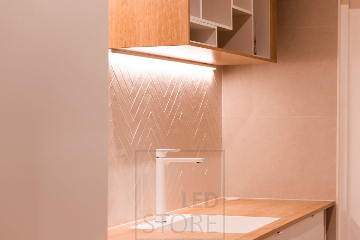 Cabinet corner with worktop lighting in the utility room. A led strip mounted next to the wall also highlights the textured tile. Ledstore.fi