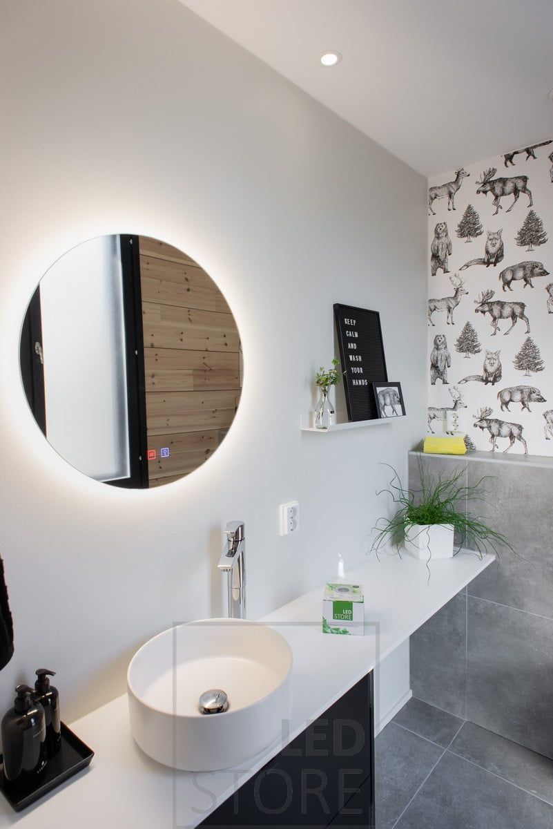 A circular light mirror and spotlights illuminating the bathroom. Ledstore.fi