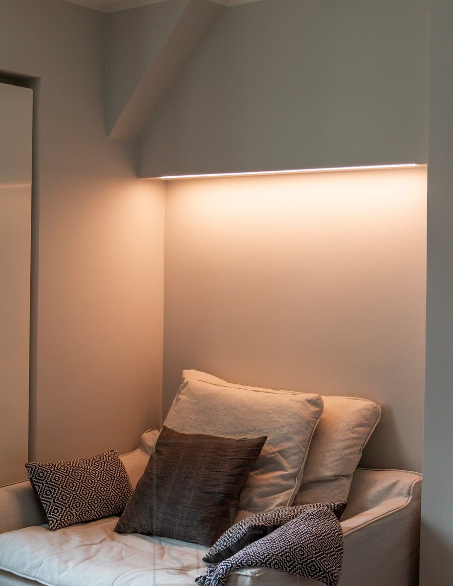Bedroom with colour temperature adjustable mood lighting above the bed, LED strip mounted on the bottom of the cabinet in a low profile surface. The light has a warm tone in the picture. Ledstore.fi