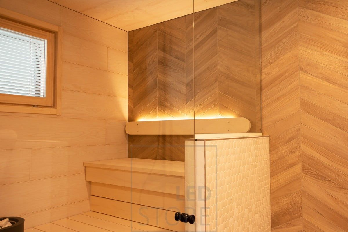 Sauna lighting implemented with a led strip on the backrest pointing upwards. The lighting in the washroom also illuminates the sauna thanks to the glass walls. Ledstore.fi