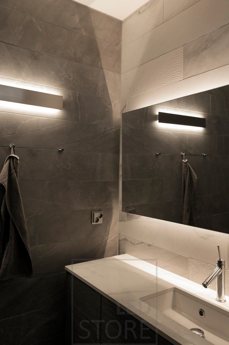 A bi-directional wall lamp and a backlit mirror to create indirect light in the toilet space. Ledstore.fi