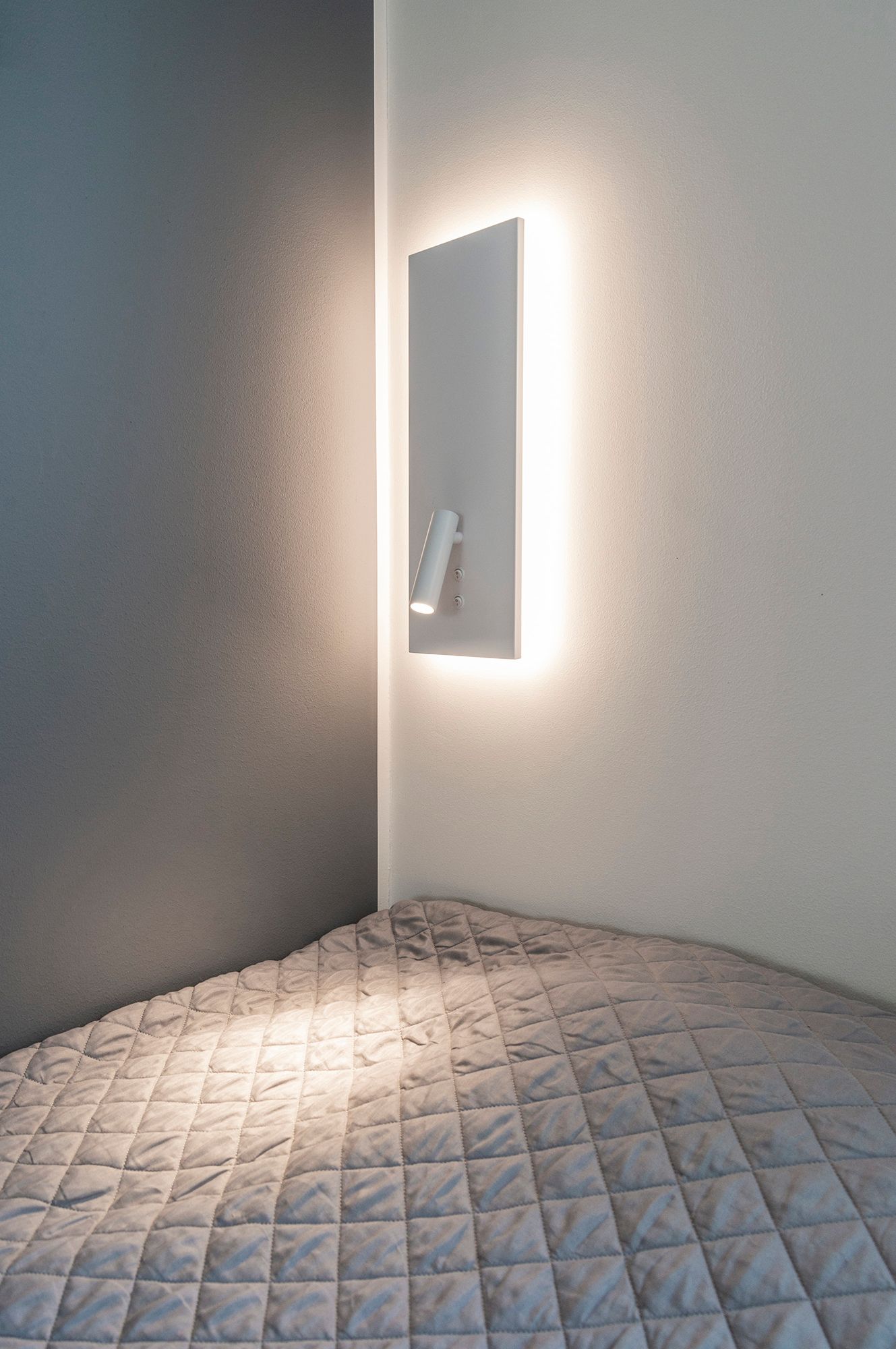 Wall lamp NIGHT in white. With indirect and soft mood lighting in the background and a directional reading light that is switched on by a separate switch. Ledstore.fi