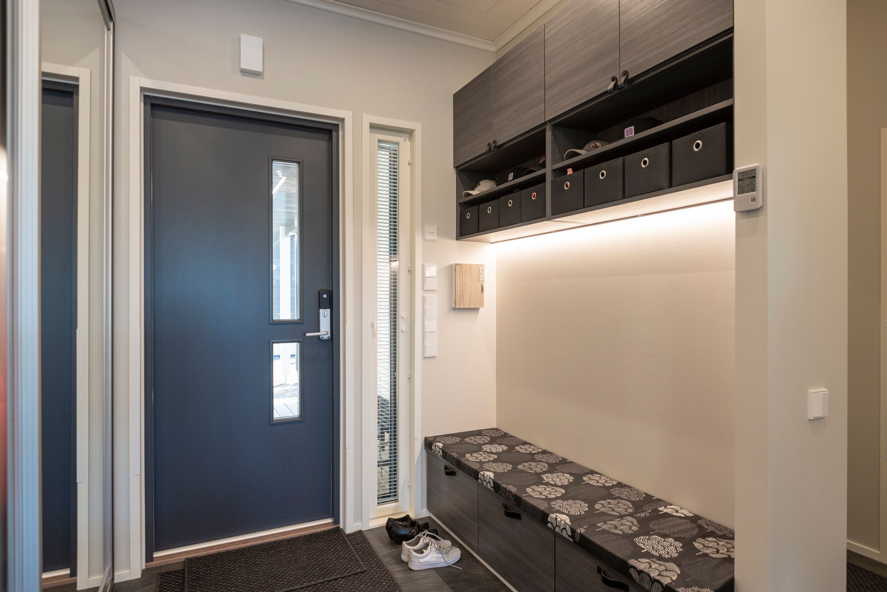 At the entrance to the hallway, above the bench, an LED strip in a low profile surface. Ledstore.fi