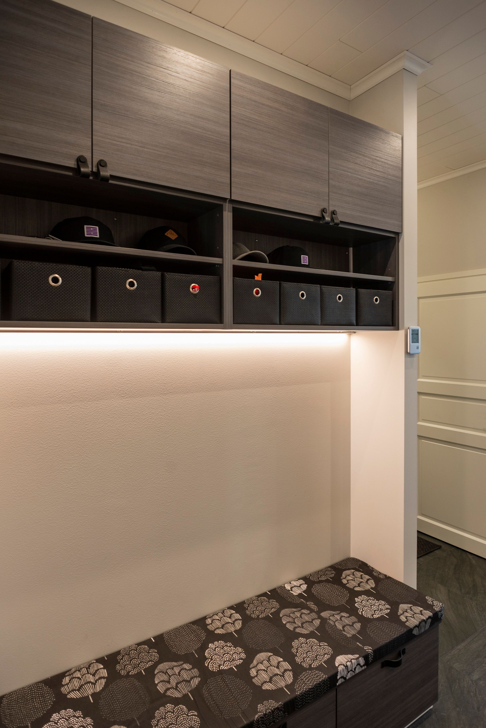 Entrance hall light in the bottom of the upper cabinet with LED strip in a low profile above the bench. Ledstore.fi