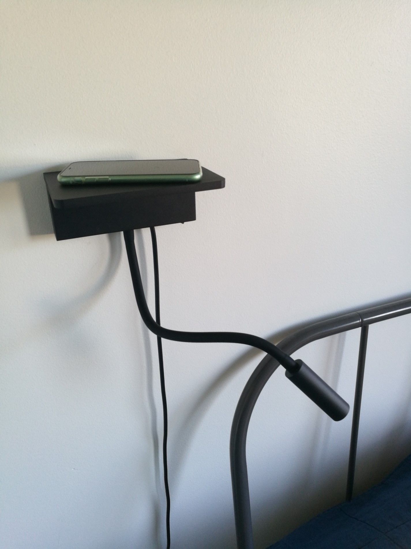 NIGHT BLADE mounted on the wall, with a phone on top of the charging platform.