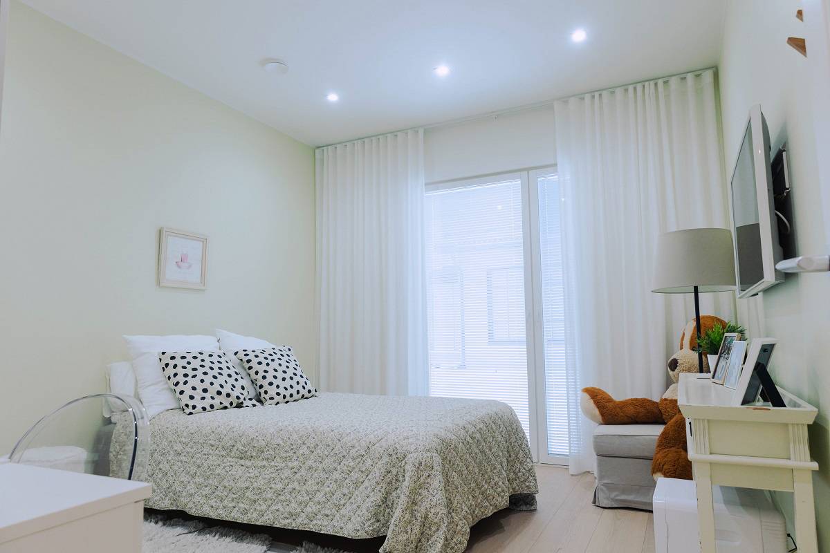 A bright and modern bedroom with a carefully made bed, white curtains and soft LED lighting. Check out LedStore.fi's latest reference projects for 2025 and get inspired for your next interior design project!