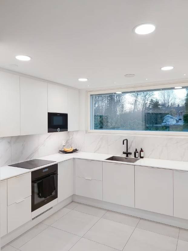 Panel lights on the kitchen ceiling, LED strip lights on the underside of the cabinets and small accent spots lined up in front of the window.  