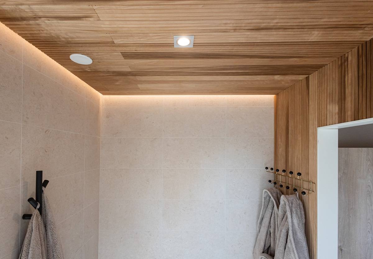 LedStore.fi offers a solution for the modern bathroom with modern LED lighting. The beige tiled walls, wooden ceiling and recessed LED lighting create a fresh and modern look. Soft grey towels hung on black hooks harmonise the minimalist interior.  