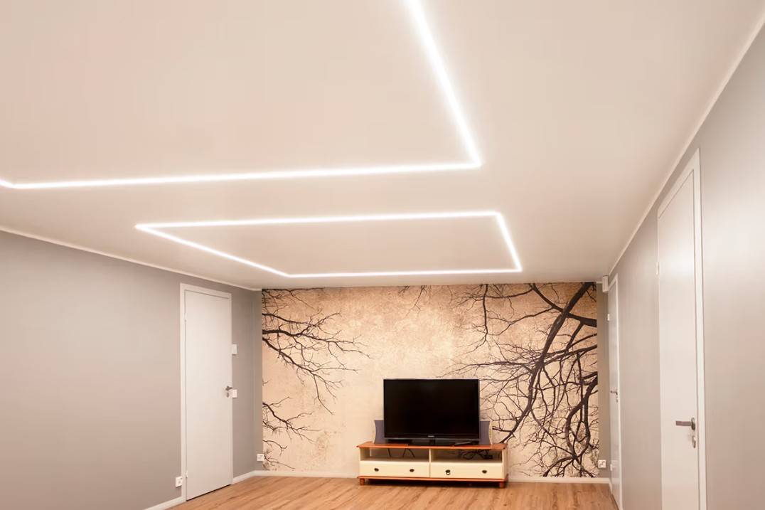 A minimalist living room in a family home in Kaitamäki, Espoo, where LED ceiling lights from LedStore.fi create a stylish lighting scheme. The living room features a TV table and a striking mural, accentuated by high-quality LED lighting.