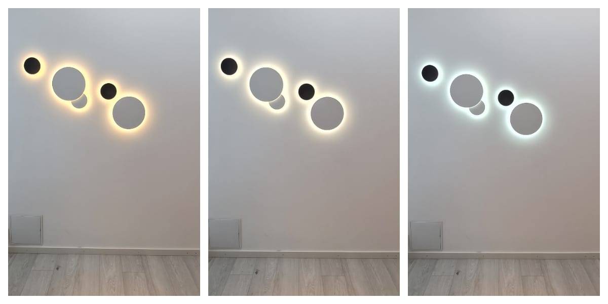 In the LedS.fi online store you can find several series of LED wall lights forming circular design elements in different sizes, perfect for the white wall. Each light creates a lighting mood: warm yellow, soft white and a cooler bluish glow. The surrounding wall and floor are in shades of grey.