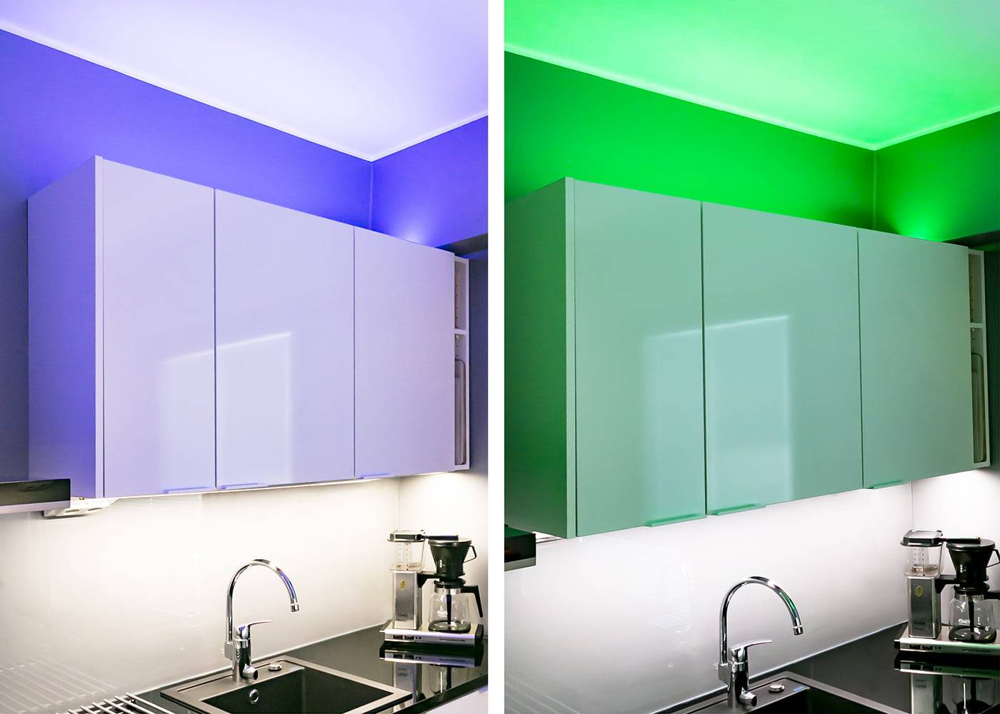 Modern kitchen with white cabinets: left side blue LED lighting, right side green LED lighting; black countertops and chrome faucet enhance style.