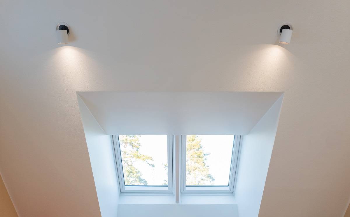 The white ceiling is equipped with two LED-doubled lights, which brightly illuminate the roof lantern. Two rectangular windows open up to the rooflight, offering views of the blue sky and treetops. This stunning lighting set is available at LedStore.fi, where a wide range of quality LED lights await you to create the perfect atmosphere in your home.
