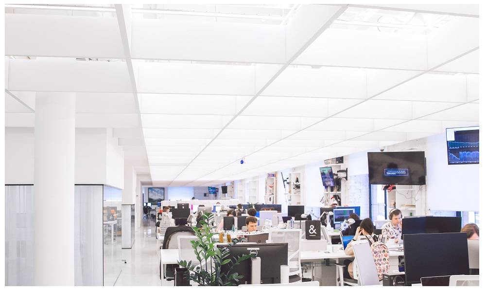Open-plan office with bright, light surfaces and plenty of workstations.