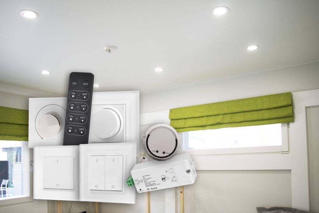 The room has recessed LED roof lights, green blinds on the window and a variety of electrical switches and remote control on display.