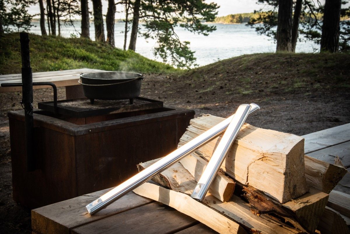 Two WANDA lamps of different lengths leaning on logs outside.